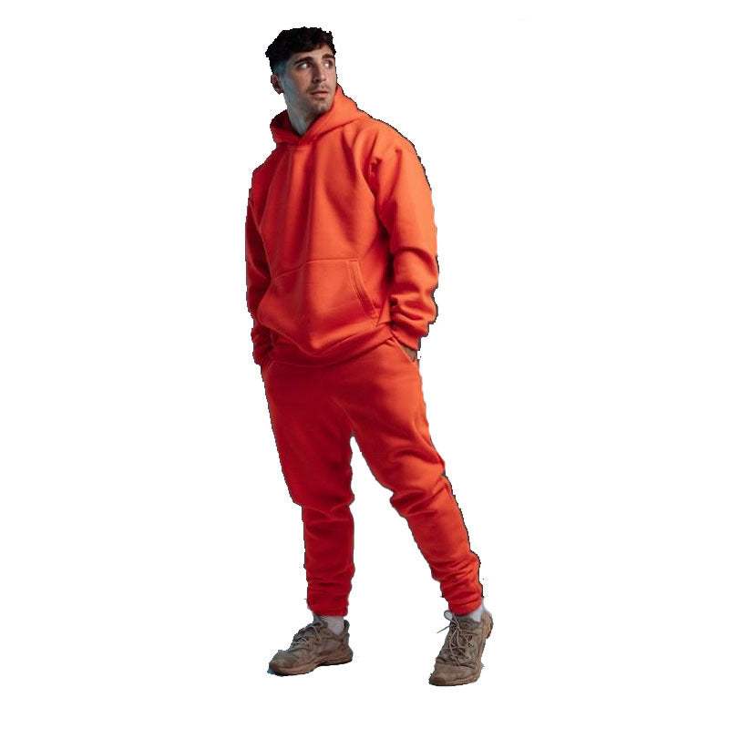 Man wearing orange hoodie two-piece set with matching joggers and sneakers isolated on white background