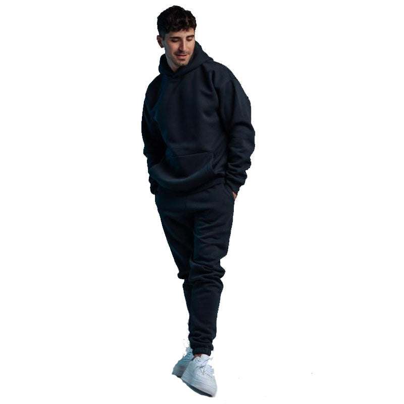 Man wearing black hoodie two-piece set with matching joggers and white sneakers isolated on white background