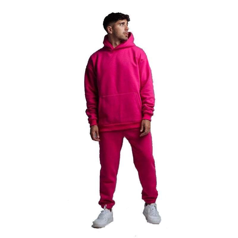 Man wearing bright pink hoodie two-piece set with jogger pants and white sneakers on white background