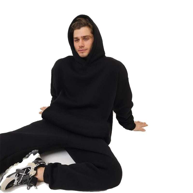 Man wearing black hoodie two-piece set sitting on the floor with sneakers