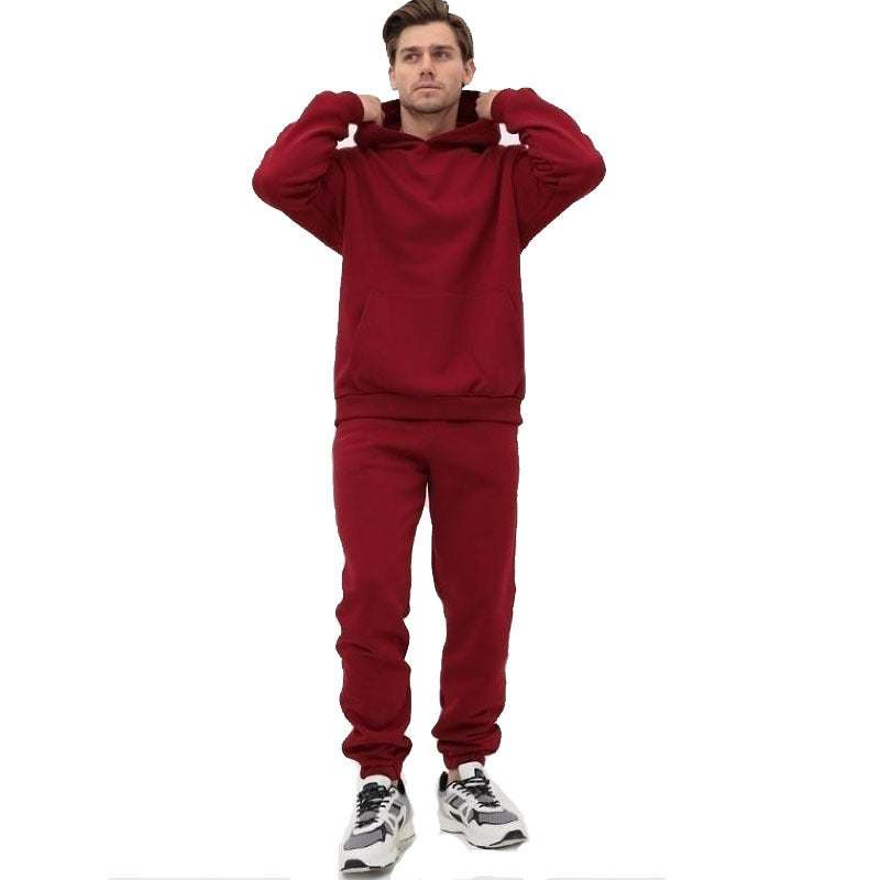 Man wearing a red hoodie two-piece set with matching joggers and sneakers in a relaxed pose