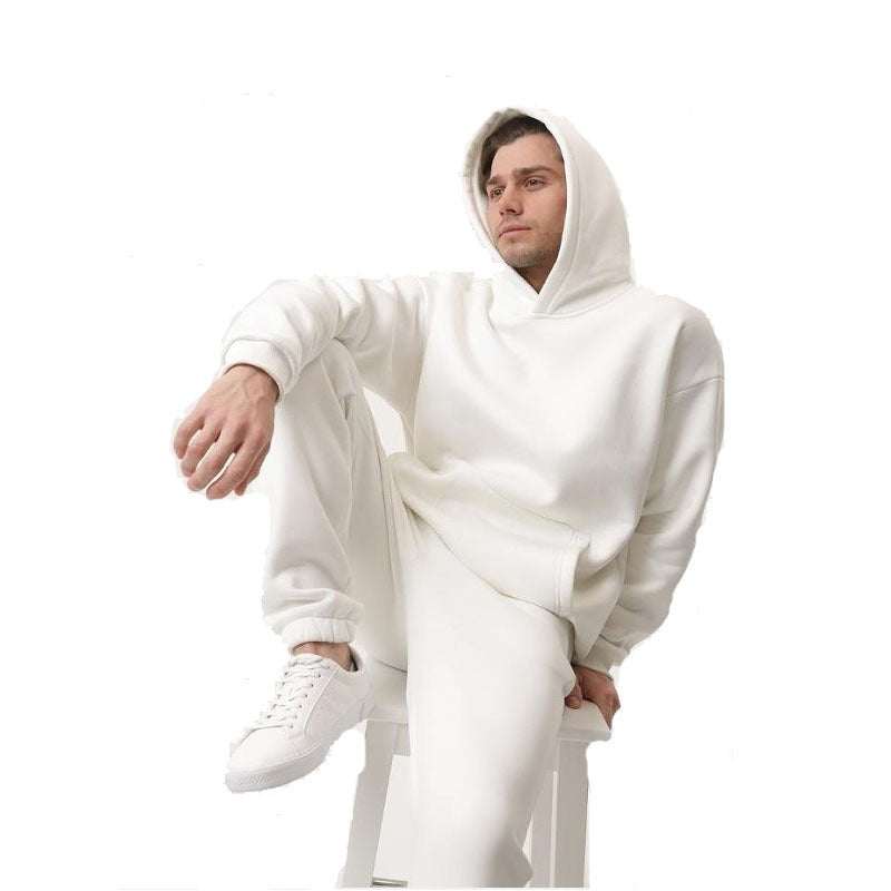 Man wearing white hoodie two-piece set with matching sweatpants sitting on stool against white background