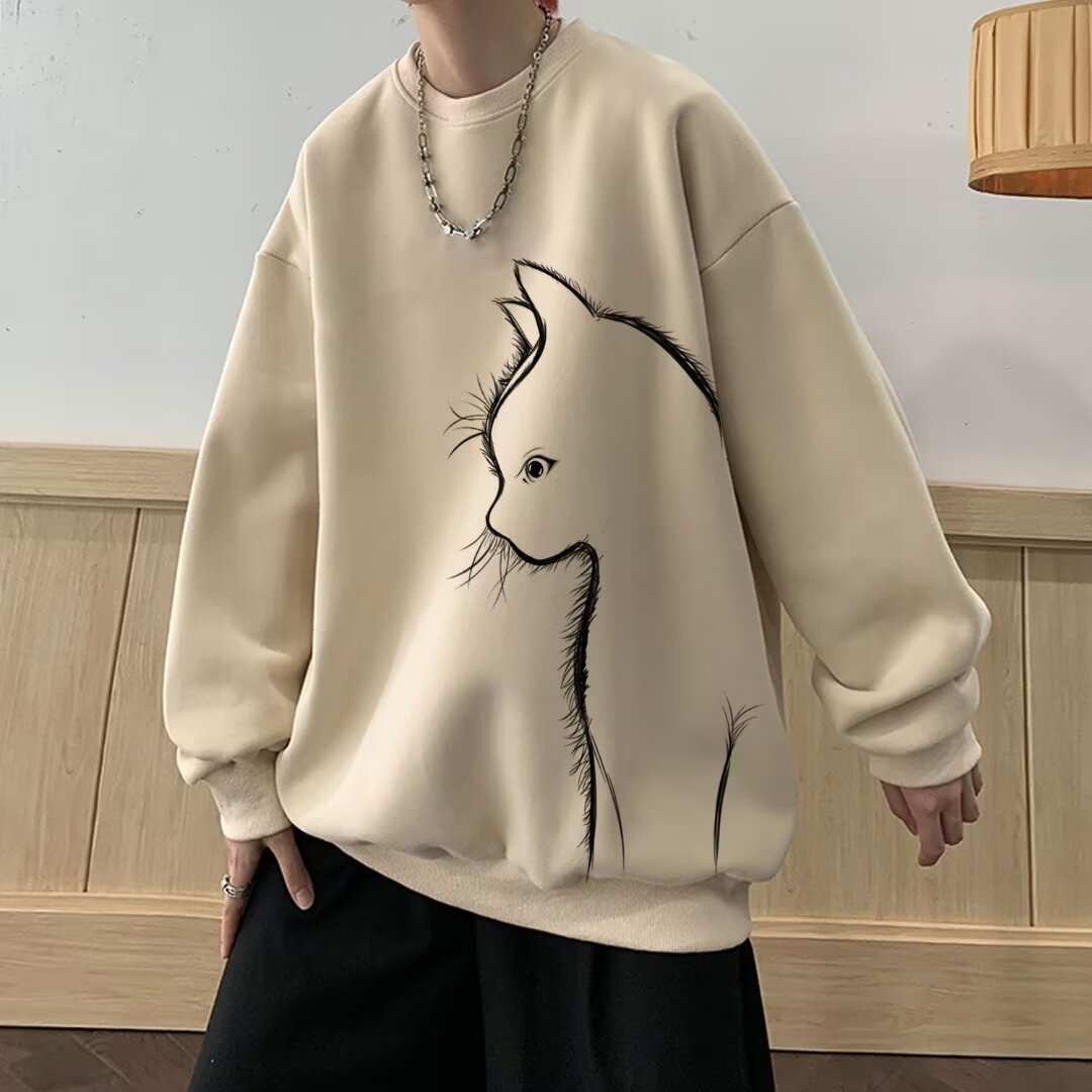 Cream-colored long sleeve sweater with round neck and black cat graphic design, styled with relaxed fit and ribbed cuffs.
