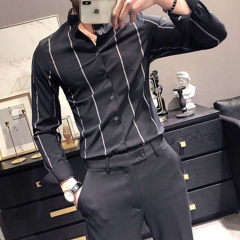 man wearing slim-fit men's striped British-style long-sleeved shirt with black pants taking a mirror selfie in a modern room