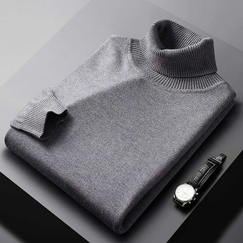 Folded grey high collar warm sweater made of soft chenille fabric next to a black wristwatch.