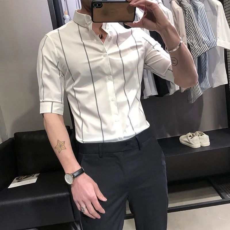 Men's striped British-style slim-fit short-sleeved shirt in white with vertical black stripes, worn with black pants.