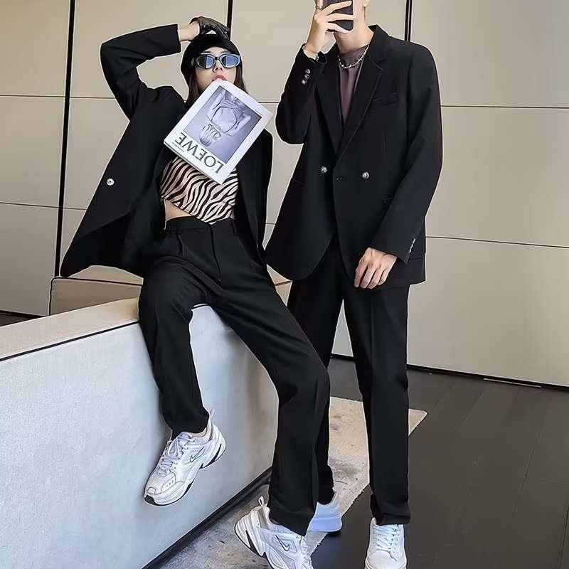 Two models wearing black men's casual draping suits with long sleeves and straight hem details.
